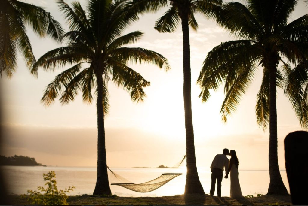 Couple relaxing by hammock at sunset on a tropical beach in Fiji – Love Island-style escape setting.