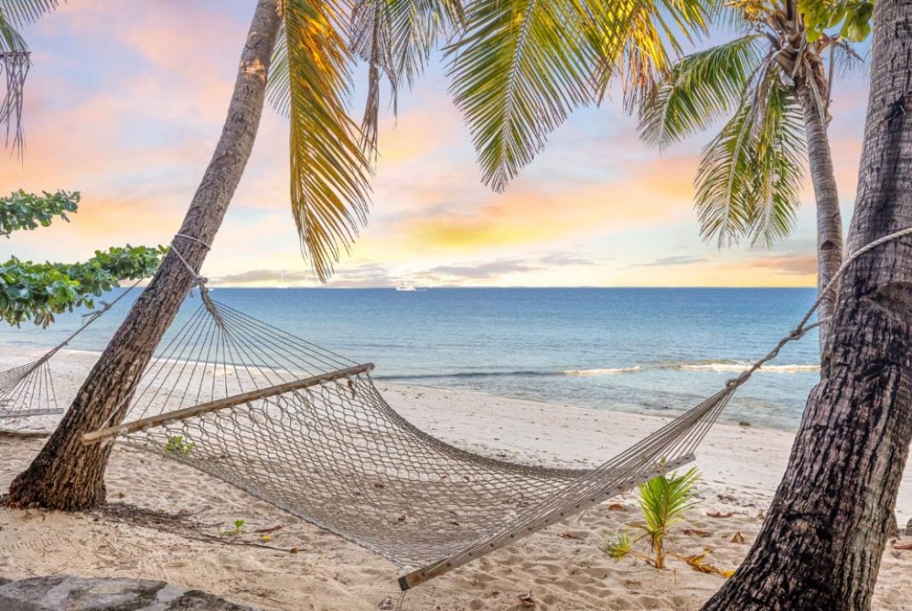 An inviting hammock overlooking the ocean at sunset, with panoramic views of the horizon. 
