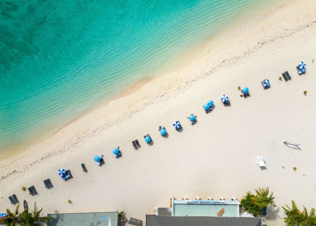 Stretch of white sandy beach with umbrellas and turquoise ocean at Beachcomber Island Resort.