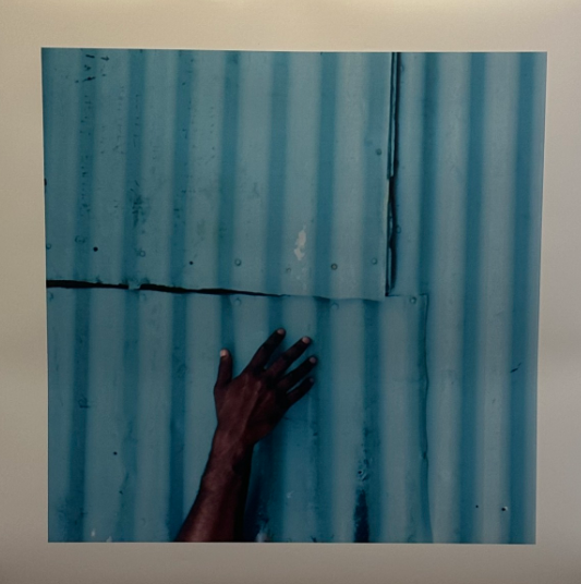 “Adventure, 2023” by Isaiah Tagilala, showing a hand on a vibrant blue surface, highlighting striking contrasts and textures in everyday urban spaces. EXPLORE Fiji photo.