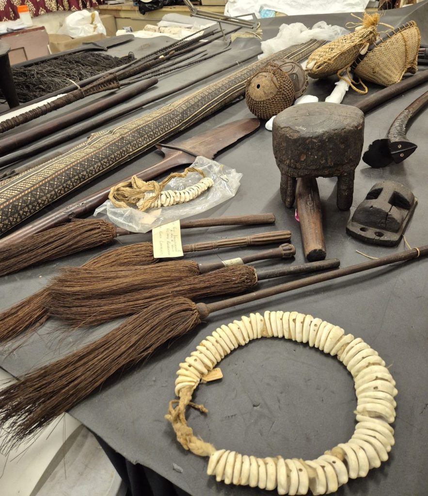 Fiji Museum artefacts including weapons, mats, and ornaments arranged on a table for the 1838 twin exhibitions.