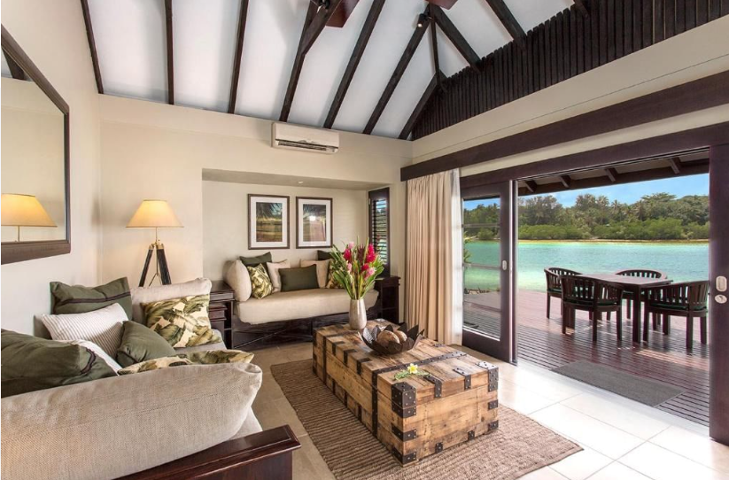 Elegant luxury resort villa interior featuring high thatched ceilings opening directly onto a private oceanfront sundeck.