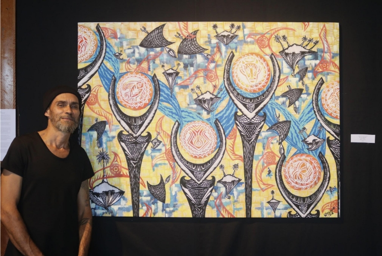 Fijian artist Josaia Waqabaca McNamara standing beside his oil painting The Great Migration
