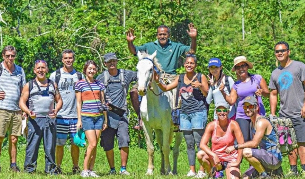 Raymond Lee (right) stands with a group of hikers in a forest clearing during a guided hiking experience in Fiji.