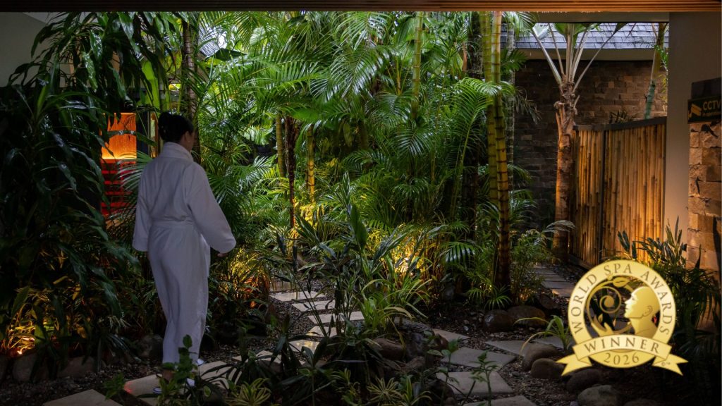 Spa InterContinental therapist in a white robe walking through the tropical garden at InterContinental Fiji Golf Resort & Spa.